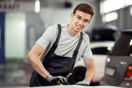 一名年轻人在汽车维修处擦亮汽车时面带微笑