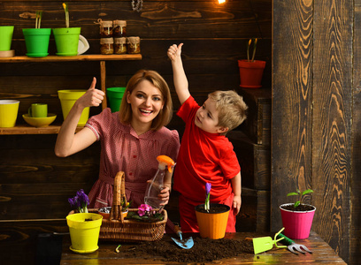 花的概念。快乐的家庭在花店竖起大拇指微笑。母子和小儿子在锅里种花。每一朵花都是在大自然中绽放的灵魂