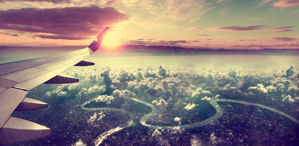 飞机旅行的概念。 飞到城市上空。 风景日落景观。 日出和云。 飞往目的地的航班和旅程