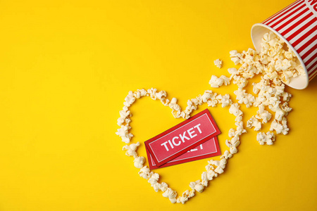 电影票和由爆米花制成的心在彩色背景顶部视图。 文本空间