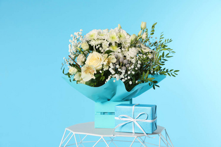 美丽的花束和礼品盒在桌子上的彩色背景