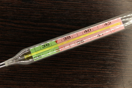 温度计在一个黑暗的木制背景上，，表明雪莱欧切奇身体的高温在摄氏度。