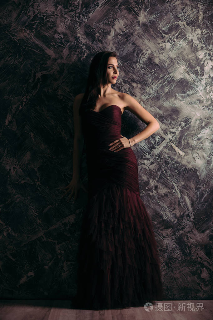 妇女在晚礼服摆姿势在黑暗的背景