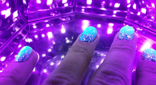 s Nails in ultraviolet lamp. Woman In Beauty Salon