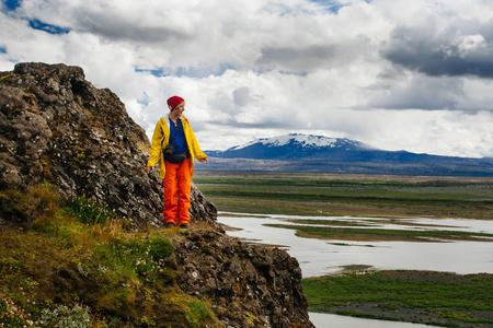 快乐的年轻女子穿着鲜艳的衣服旅行冰岛，享受大自然