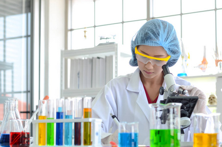 实验室里的女科学家用显微镜做实验。 医疗保健技术和药物研发的照片概念。