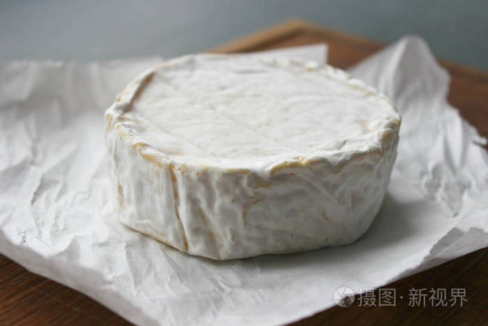 卡蒙伯特奶酪关门了. 白色纸上的圆形卡蒙伯特奶酪,树的背景. 美食奶