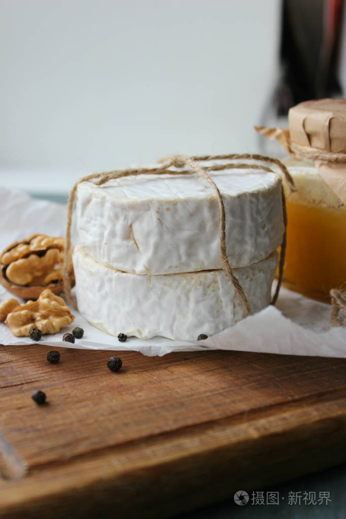 白色纸上的圆形卡蒙伯特奶酪,树的背景.