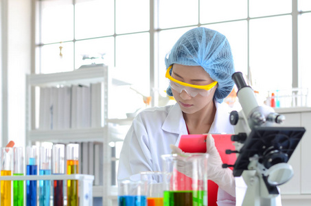 实验室的女科学家用化学液体做实验，做清单，并记录实验室测试的数据。