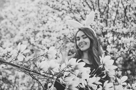 在玉兰树上用彩色红鸡蛋微笑的快乐女人
