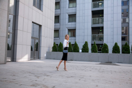 办公楼前的年轻商务女性。 她穿着一件白衬衫