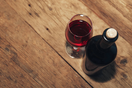 红酒瓶和一杯旧木桌上的葡萄酒。