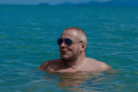 太阳要落山了太阳落山时,戴墨镜的人在海边摆姿势照片