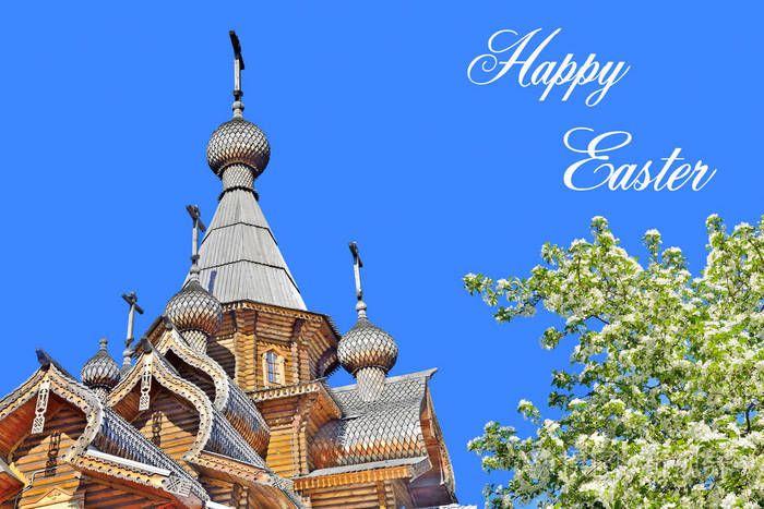 美丽的基督教木制教堂和十字架,在晴朗的蓝天背景上开着白花的苹果树