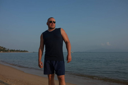 太阳要落山了太阳落山时,戴墨镜的人在海边摆姿势照片