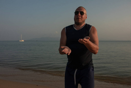 太阳要落山了太阳落山时,戴墨镜的人在海边摆姿势照片