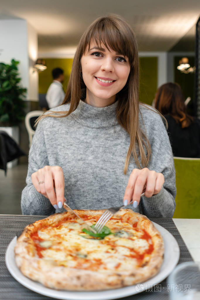 吃披萨的年轻女子的肖像那不勒斯比萨饼从燃木炉在一家意大利餐馆吃