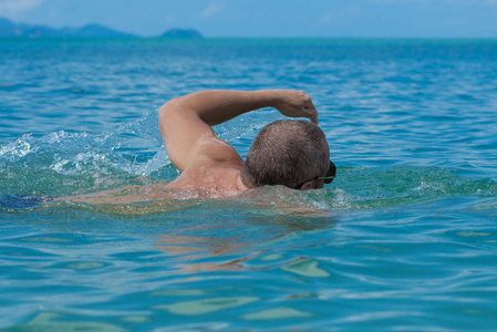 戴墨镜的男运动员在海里的水里游泳照片