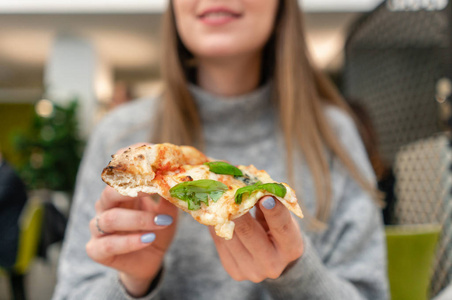 吃披萨的年轻女子的肖像。那不勒斯比萨饼从燃木炉。在一家意大利餐馆吃午饭靠近一个大窗户的桌子。玛嘉丽塔和四块奶酪