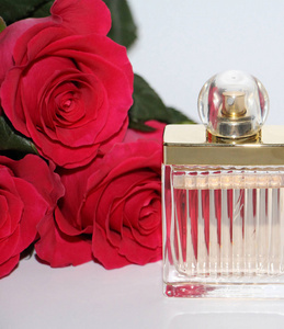 照片中有一朵红玫瑰香水和珍珠。 白色背景上的照片。