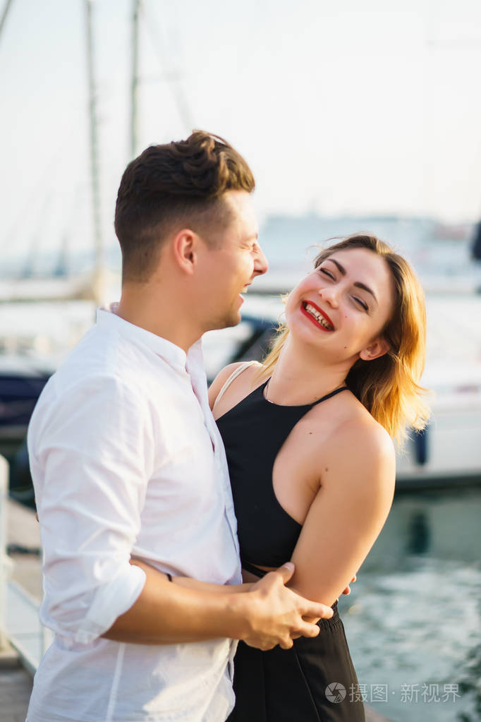 幸福的一对相爱的夫妇在港口笑着散步