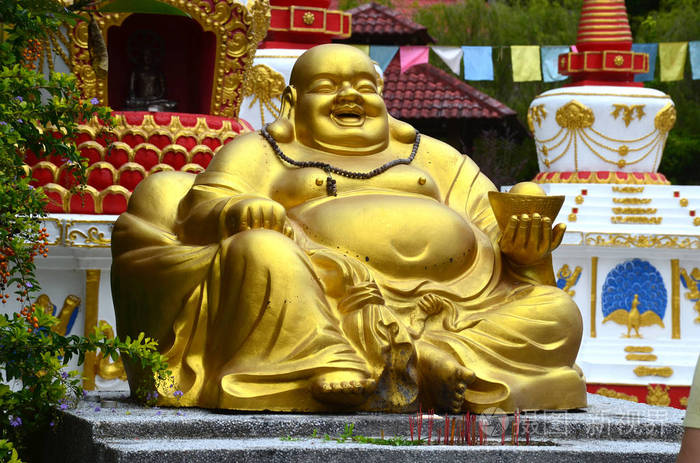 大金雕像坐笑佛陀在瓦特科万纳拉尔兰卡维岛马来西亚。 幸运寺，石岩上有雕刻的佛陀。 亚洲文化与建筑