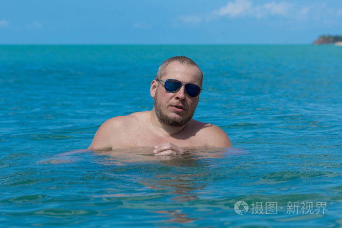 戴墨镜的男运动员在海里的水里游泳