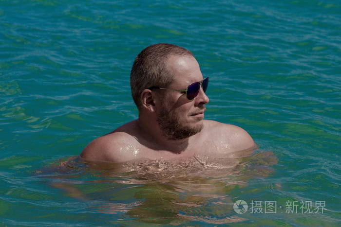 日落时分戴太阳镜的晒黑的人在海边摆姿势