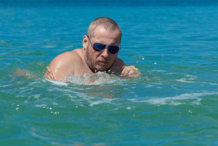 戴墨镜的男运动员在海里的水里游泳照片