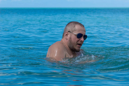 戴墨镜的男运动员在海里的水里游泳照片