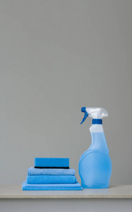 用塑料分配器海绵和布清洁蓝色喷雾瓶，以防止灰色背景上的灰尘。清洁工具。复制空间。