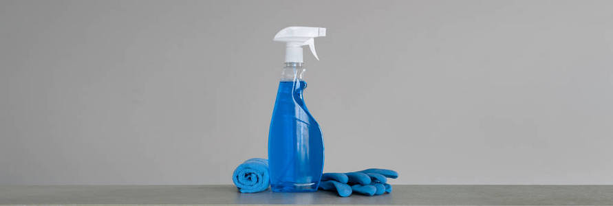用塑料分配器万寿菊和布清洁蓝色喷雾瓶，以防止灰色背景上的灰尘。清洁工具。复制空间。