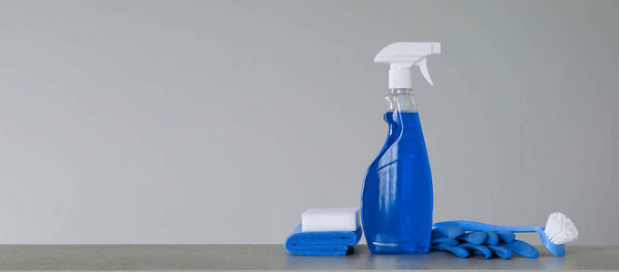 用塑料分配器清洗蓝色喷雾瓶，用刷子擦洗盘子，用布擦灰尘，用海绵和橡胶手套在灰色背景上。清洁设备。复制空间。