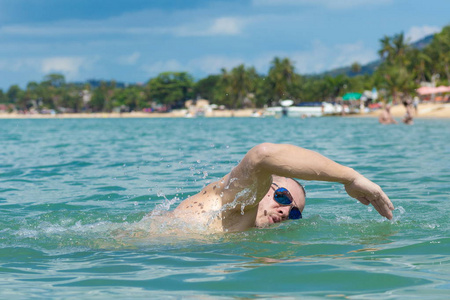 戴墨镜的男运动员在海里的水里游泳照片