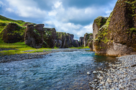 陡峭的悬崖，长满了绿色的苔藓，周围是一条非常快的河流，有着冷水。冰岛峡谷童话和传说