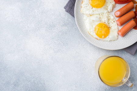 煎鸡蛋和香肠西红柿在盘子里。 概念早餐。