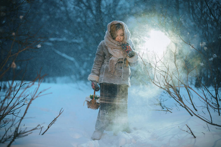 小女孩带着篮子去寻找冬天在森林里的雪下的第一朵花