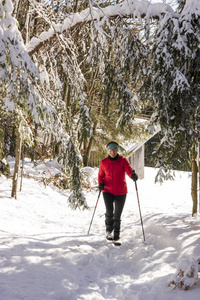 冬天快乐的女人走在雪地里的户外自然。 快乐的人放松在雪林景观的户外散步活动，戴着温暖的红色时尚外套，夹克，靴子，围巾帽子。