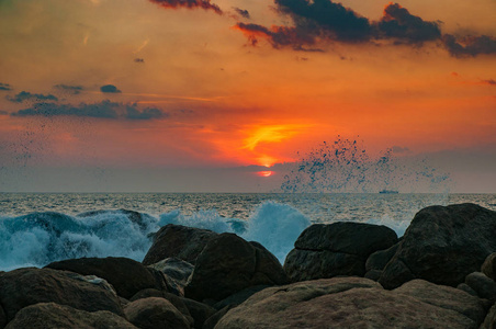 日落时海浪在岩石上破碎。 夕阳在海洋中，海浪在岩石上破碎。