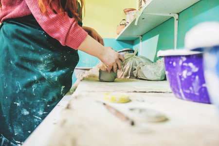 女陶家手在陶器车间的桌子上塑造粘土。