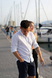 幸福的一对相爱的夫妇在港口笑着散步
