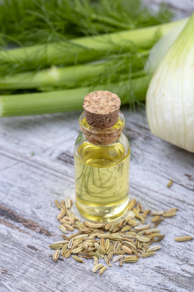 一瓶茴香精油背景是新鲜的绿色茴香小枝和茴香种子