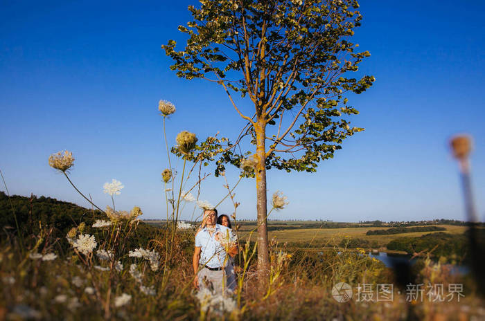 一对相爱的夫妇在夏天的山上散步,轻轻地牵着手