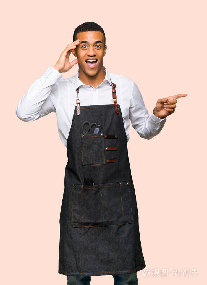 年轻的afro美国理发师指着一边,在孤立的背景上展示一种产品