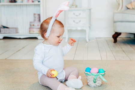 复活节戴着兔子耳朵玩彩蛋的小女孩