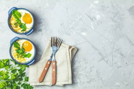 蓝色陶瓷烘焙模具中的烘焙鸡蛋。 从蔬菜和鸡蛋中分菜，意大利或法国风格。 鸡蛋可可可可可早餐。 顶部视图复制空间为您的文本。