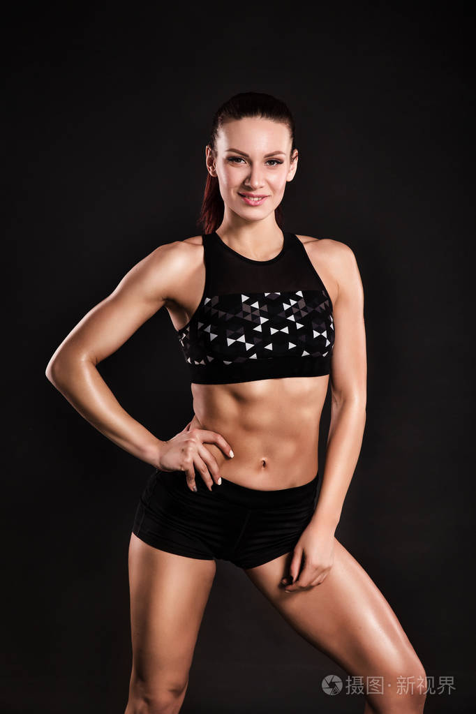 强壮的女性健美运动员与完美的腹肌肩膀二头肌三头肌和胸部黑色背景上