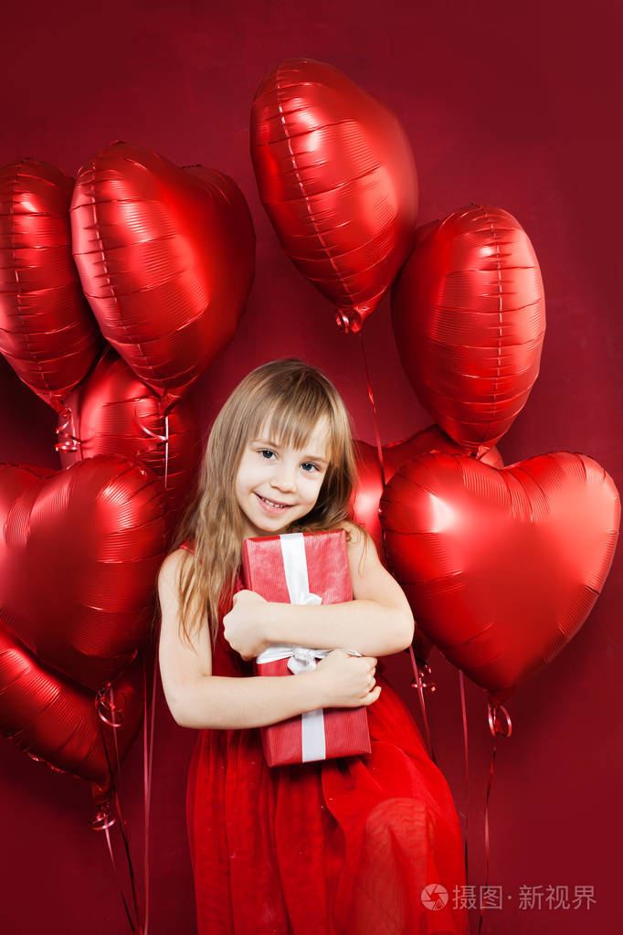 快乐的小女孩带着红色气球和生日礼物在气球派对庆祝背景上漂亮的孩子
