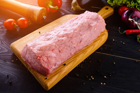 生猪肉。 新鲜牛排在木切割板上的深色背景和复制空间为您的文本。 蔬菜和香料的牛柳