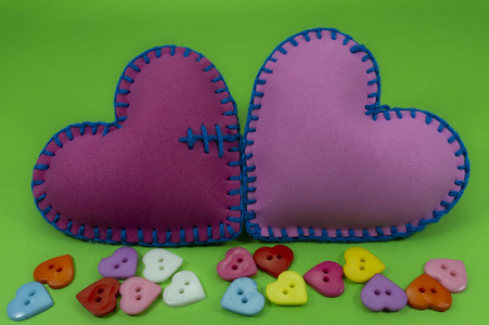 心形手工缝制的纺织心,由粉红色织物制成,用蓝色线缝在绿色染色背景上